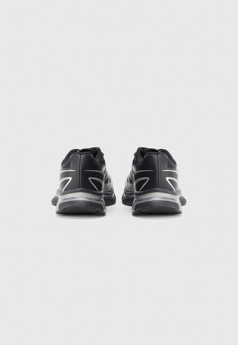 Black athletic shoes featuring a textured fabric upper, rounded toe, and reflective accents. Rear view shows a low-profile design with cushioning.
