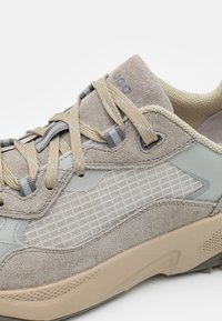 Sneaker in suede beige e grigio con pannello laterale in tessuto testurizzato, lacci beige, colletto imbottito e suola spessa e ammortizzata.