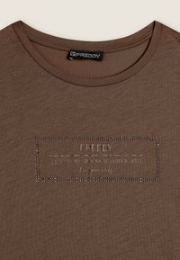 T-shirt marrone a maniche corte con collo rotondo. Presenta un design del logo testurizzato in un motivo rettangolare, abbellito con accenti metallici.