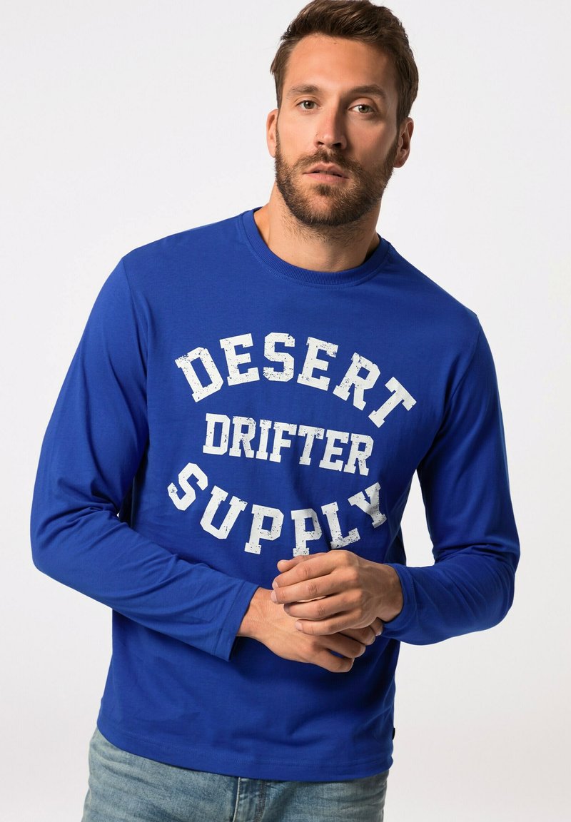 Camicia a maniche lunghe blu con una grafica bianca invecchiata che recita "DESERT DRIFTER SUPPLY" sul petto. Vestibilità casual e tessuto morbido.