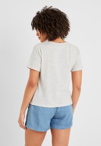 Light gray short-sleeve t-shirt made of speckled fabric with a round neckline, paired with blue denim shorts.