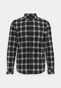 Camicia in flanella a quadri nera e grigia con maniche lunghe, colletto con bottoni e tasca sul lato sinistro. Tessuto morbido e testurizzato.