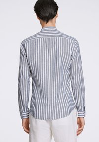 Langærmet shirt in blauw en witte verticale strepen, gemaakt van een gestructureerde stof. Bevat een klassieke kraag en knoopmanchetten.