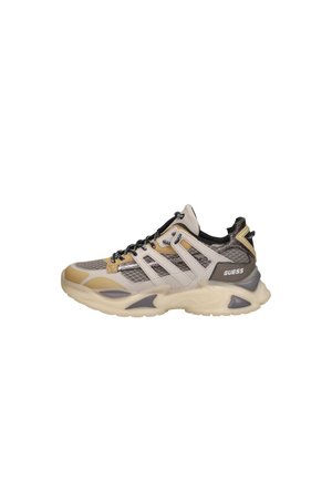 Sneaker robusta beige e grigia con pannelli in mesh, lacci neri e logo "GUESS" sul lato, progettata per un uso casual o atletico.