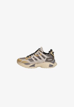 Baskets beige et grises épaisses avec des panneaux en mesh, des lacets noirs, et le logo « GUESS » sur le côté, conçues pour un usage décontracté ou sportif.