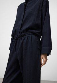 Marineblaues Zweiteiler-Outfit mit einem strukturierten Hemd mit Knöpfen und Hose mit elastischem Bund, mit einem dezenten Streifenmuster und verstellbarem Kordelzug.