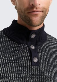 Strickpullover mit einem gerippten navyfarbenen Kragen, der ein strukturiertes Muster aufweist, sowie drei grauen Knöpfen und einem taillierten Schnitt.