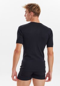 Sort kortærmet t-shirt med rund hals, lavet af glat stof. Tætsiddende design med en ensartet tekstur og ingen synlige mønstre eller hardware.