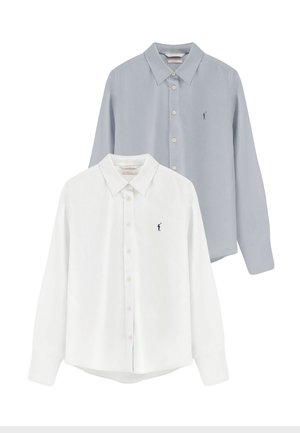Dos camisas de manga larga con botones, una blanca y una azul clara, cada una con un pequeño logo de golfista bordado en el pecho.