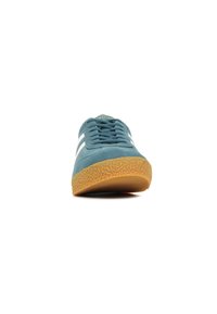 Ljusblå mockaskor med vita ränder, gummisulor, rund tå och texturerad sula. Har snören och varumärkesdetalj på tungan.