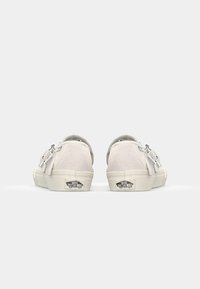 Canvas sneakers med en ljus beige ovandel, gummisula och snörningsdesign. Har dekorativa kvastar och logotyp på hälen.