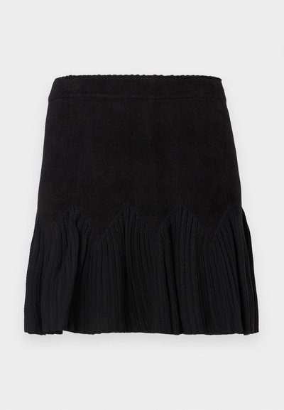 Schwarze Rock mit einem strukturierten, gerippten Design und einem wellenförmigen Saum. Der Stoff hat eine weiche Haptik und der Bund ist glatt für zusätzlichen Komfort.