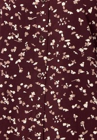 Bordeaux blouse met een bloemmotief in crème en grijs, met een knoopsluiting aan de voorkant en een gladde stoftextuur.