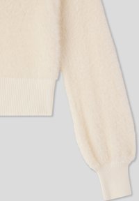 Sweter w kremowym kolorze o miękkiej, puszystej fakturze. Posiada ściągacze na mankietach i luźny krój. Nadaje się do noszenia warstwowego w chłodniejszą pogodę.