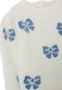 Maglione bianco morbido con motivi a fiocco blu, scollatura rotonda e tessuto strutturato. Aspetto morbido e accogliente con una finitura tattile.