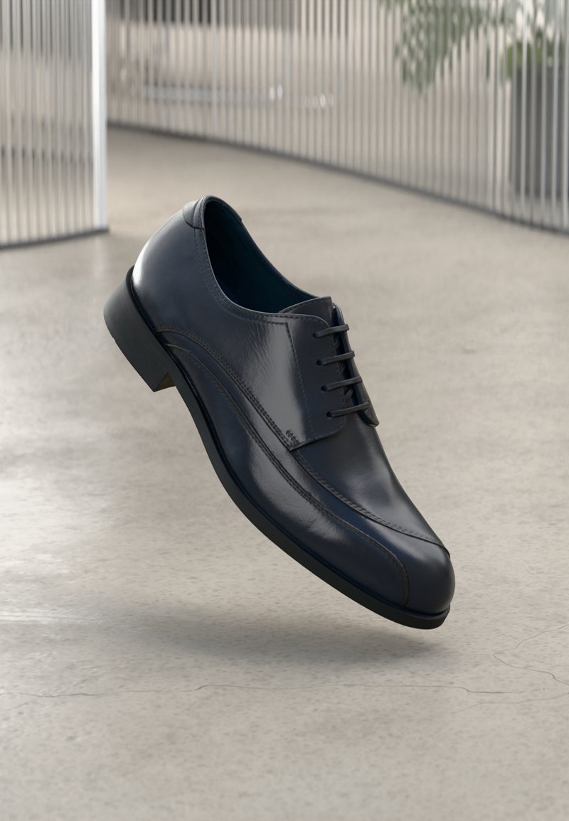 Glossy black leather dress shoe with laces, floating above a smooth, light gray floor and vertical metallic bars in the background.