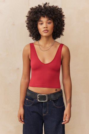Rotes geripptes Tanktop mit tiefem V-Ausschnitt, kombiniert mit hoch taillierten dunklen Jeans und einem schwarzen Gürtel mit Metallverschluss.