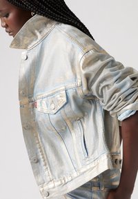 Metallblå denimjacka med en strukturerad design, nedfällbar krage, framfickor och silverdetaljer, med uppvikta ärmar och stickade detaljer.