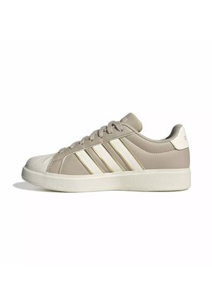 Beige Adidas sneaker met witte zool en drie witte strepen aan de zijkant, vetersluiting en gevoerde kraag, zijaanzicht.