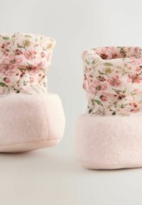 Stivali in pantofole rosa con motivo floreale, morbidi e con polsino a coste. La parte inferiore è realizzata in materiale peloso, per offrire calore e comfort.