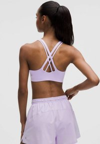 Lila sportbh med korsad ryggdesign, tillverkad av stretchy material; tillsammans med matchande lila shorts med elastisk midja.