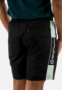 Pantalones cortos negros con un acabado texturizado, que cuentan con un panel lateral de color verde menta claro, cinturilla elástica y un pequeño bolsillo trasero con cremallera.