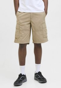 Khaki cargo shorts featuring multiple side pockets, reinforced stitching, and a relaxed fit. Worn with black sneakers and white socks.