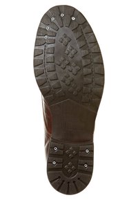 Suola di stivale in pelle marrone con un motivo di battistrada robusto, dotata di molteplici tasselli di trazione e borchie metalliche per una maggiore aderenza e durata.