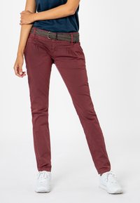 Burgundy slim-fit pants with a textured woven belt. Cotton material, side pockets, and a smooth finish. Paired with white sneakers.
