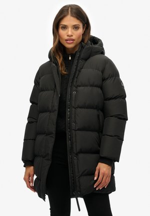 Sort pufferjakke med hætte, der har et quiltet design, frontlynlås og sidelommer. Lavet af glat, isoleret materiale.