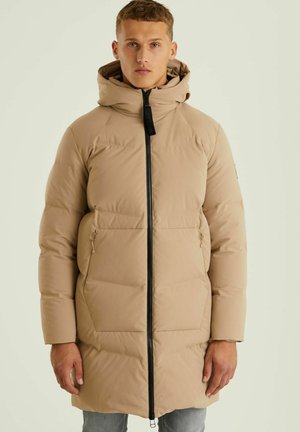 Abrigo tipo puff en beige claro, con cierre de cremallera, capucha y bolsillos laterales. Fabricado en un material suave e insulated con un diseño acolchado.