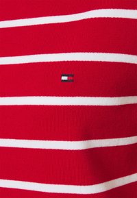 Pullover rosso a maglia con strisce orizzontali bianche, dotato di un piccolo logo ricamato in blu navy, rosso e bianco sul petto.
