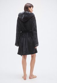 Albornoz de felpa negro con capucha, forrado con estampado de leopardo y mangas largas. Incluye cinturón a la cintura y tejido texturizado.