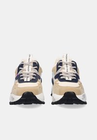 Par de zapatillas beige con suelas negras, acentos en azul marino y blanco, cordones con patrón y tiradores blancos etiquetados como "FASHION" vistos de frente.