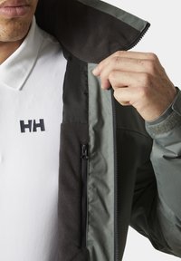 Waterdichte jas met een donkergrijze buitenkant, zachte fleece voering en een ritszak. Aangevuld met een gemustreerde binnenkraag.