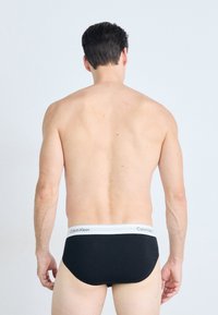 Fekete Calvin Klein alsónadrág szürke derékkal. Az anyaga simának és testhezállónak tűnik, kiemelve a mintázat nélküli minimalista designt.