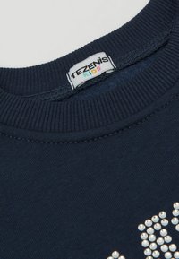 Námořnická modrá bavlněná mikina s žebrovaným kulatým výstřihem. Na přední straně má lesklé bílé kamínky v vzoru a štítek "Tezenis Kids".