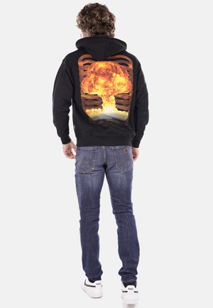 Felpa nera con cappuccio caratterizzata da una grande grafica di un'esplosione sul retro. Si abbina bene a jeans blu e sneaker bianche.