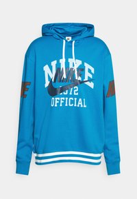 Blå bomullshuvtröja med en framkänguruficka, vita och svarta Nike-logo grafiker, samt randiga vita detaljer vid fållen och ärmslut.