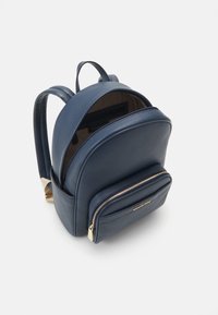 Zaino in pelle blu con forma arrotondata, superficie testurizzata, dettagli in zipper dorati e tasca frontale. Interno di colore beige.