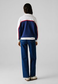 Mikina s farebnými blokmi v námorníckej modrej, bielej a červenej farbe. Má voľný strih, rebrované manžety a logo 'PEPE JEANS' na zadnej strane.