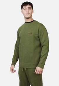 Felpa verde oliva, design a girocollo, con polsini e orlo a costine, presenta un piccolo logo multicolore sul petto, in morbido tessuto misto cotone.