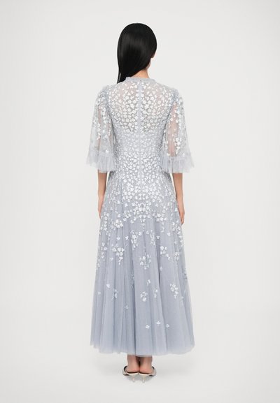 Długa szara suknia z kwiatowym haftem, przezroczystymi rękawami i warstwową spódnicą z tiulu. Posiada wysoką linię dekoltu i dopasowany gorset.