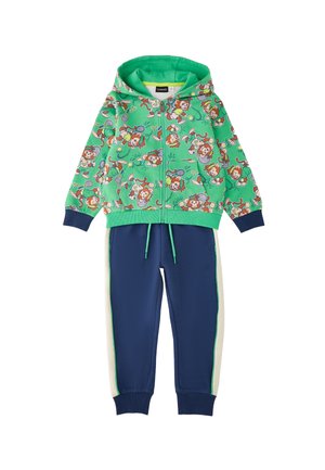 Chaqueta verde con capucha y cremallera con estampado de mono de tenis divertido combinada con pantalones jogger azul marino con rayas blancas en los laterales y cintura con cordón.