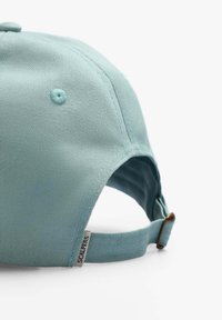 Helleblaue Baseballmütze aus einem strukturierten Stoff, verstellbarer Riemen hinten und einem kleinen Label, das an der Seite angenäht ist.