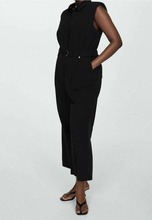 Musta ilmanhiha jumpsuit etupainonappikiinnityksellä, vyötäröllä vyö ja sivutaskut. Sileä kangas, rento malli ja kapenevat lahkeet.