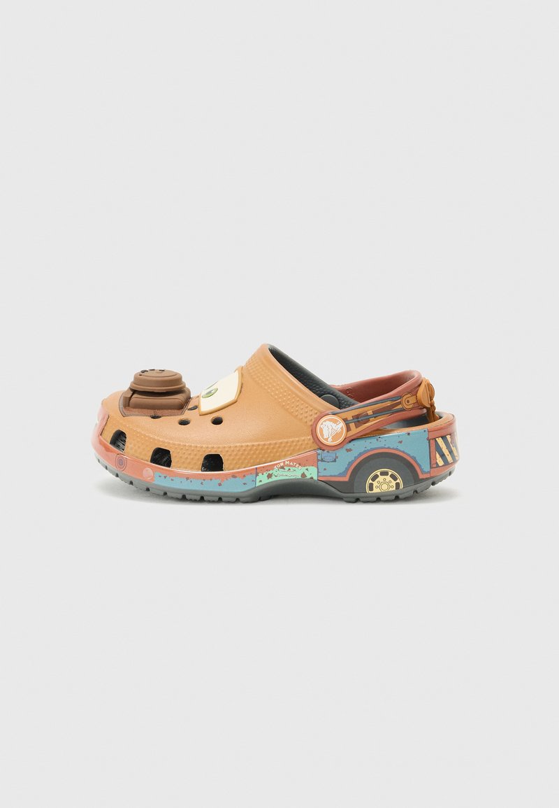 Crocs laranja com um design em cartoon, apresentando um acento circular castanho, orifícios de ventilação e uma base padronizada em azul e verde.