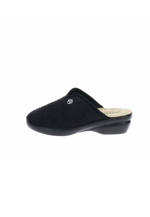 Zapatilla negra de interior sin cordones con parte superior texturizada, tacón ligero y pequeño emblema redondo plateado en el lateral.