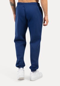 Dunkelblaue Jogginghose mit einem elastischen Bund und Bündchen, aus weichem Stoff hergestellt. Verfügt über seitliche Taschen für zusätzlichen Komfort.