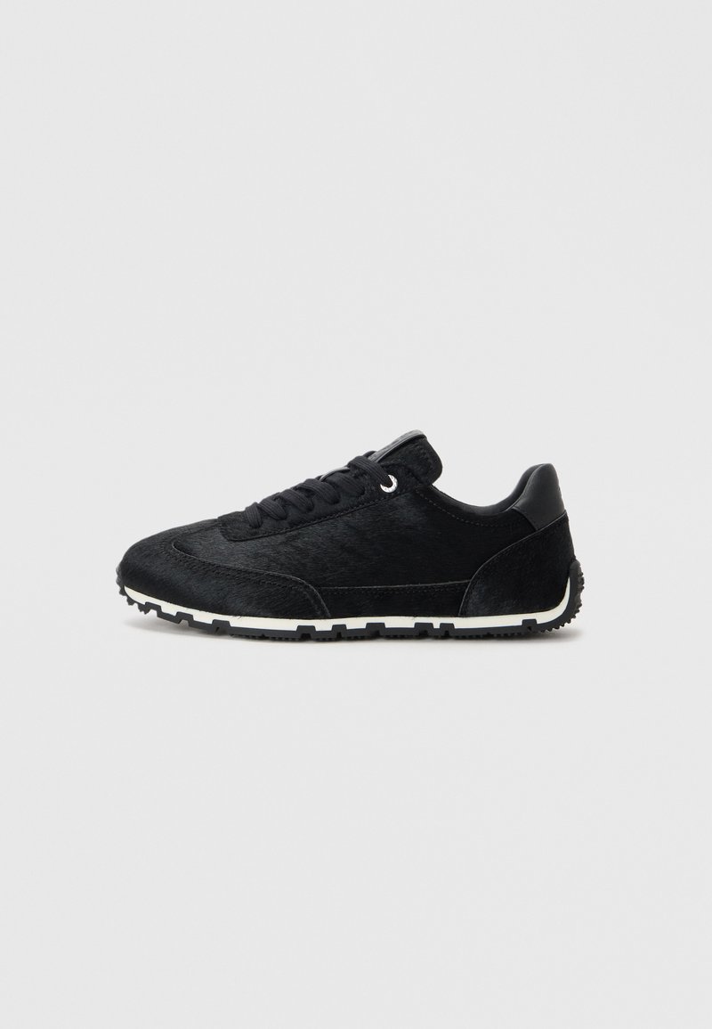 Tenisi negri fabricați dintr-un material textil neted, cu accente de suede. Au un design de tip low-top, vârf rotund și talpa albă cu un model texturat pentru aderență.